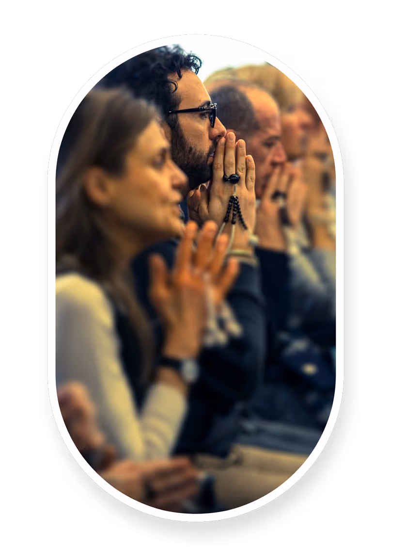 Persone sedute a mani giunte recitano daimoku